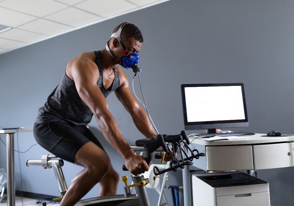 Man on stationary bike with oxygen mask on