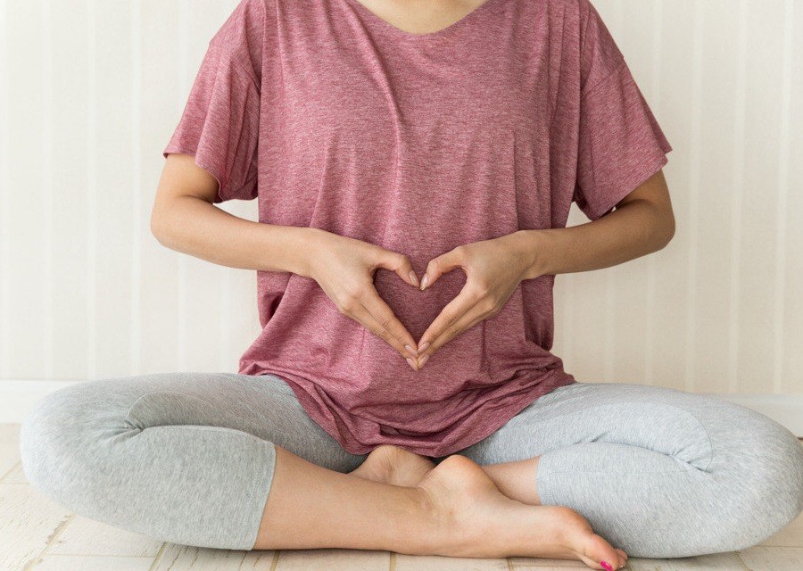 Woman sitting in yoga pose with heart shape made with hands